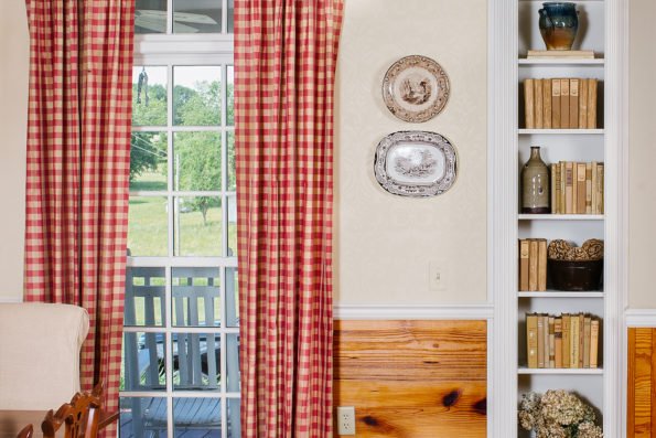 Southern flannel style drapes, decorative plates, and a shelf of books add dimension to this southern decor. 